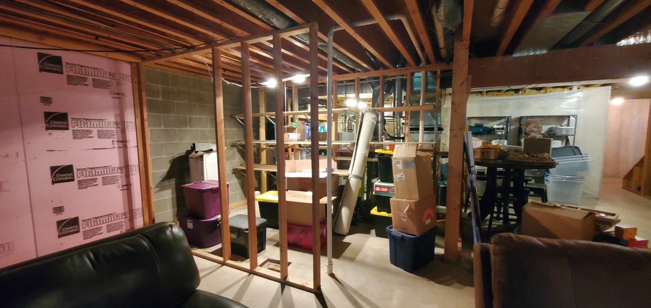 Dimmly lite basement family room, unfinished bathroom and storage area.